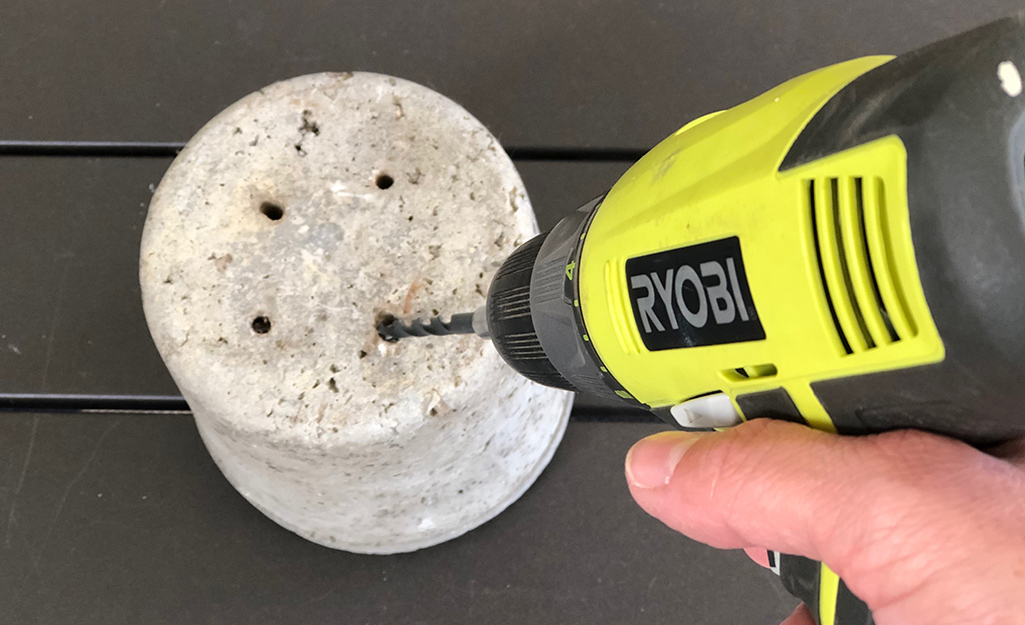 A gardener drills holes in the rustic hypertufa container.