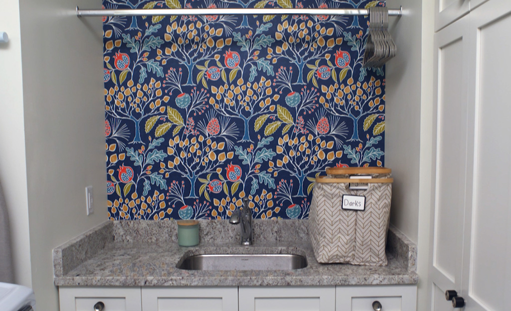 A colorful wallpaper hung over a laundry sink.