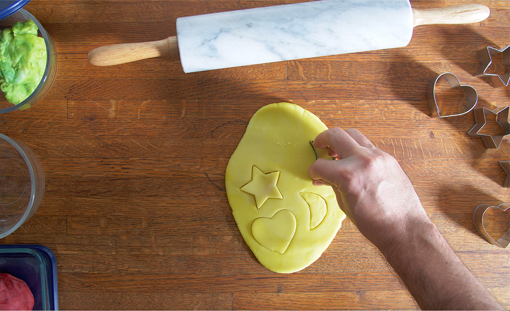 A person uses a cookie cutter to make shapes in dough.