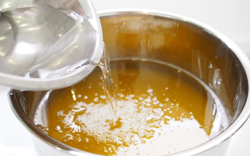A person pouring clear liquid into a bowl. A person pouring clear liquid into a bowl.