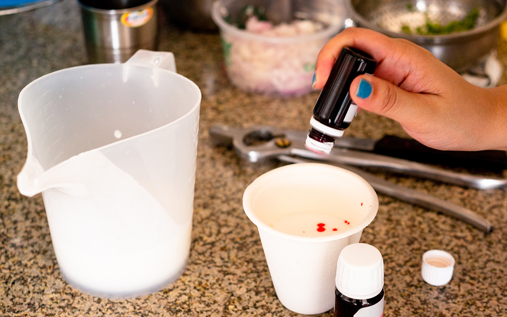 A person adding coloring to a cup. A person adding coloring to a cup.