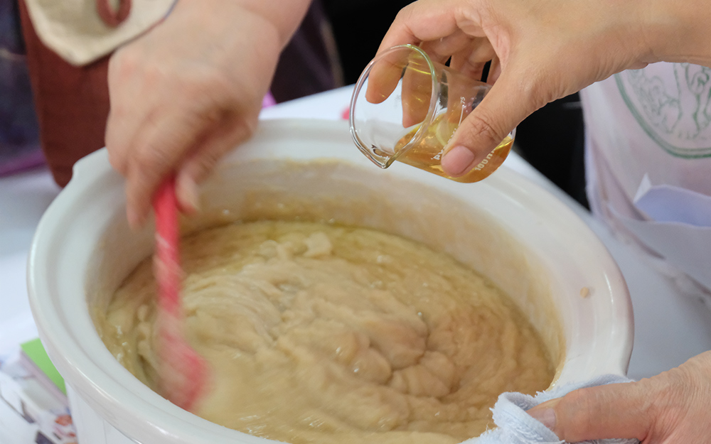 A person mixing soap in a slow cooker. A person mixing soap in a slow cooker.