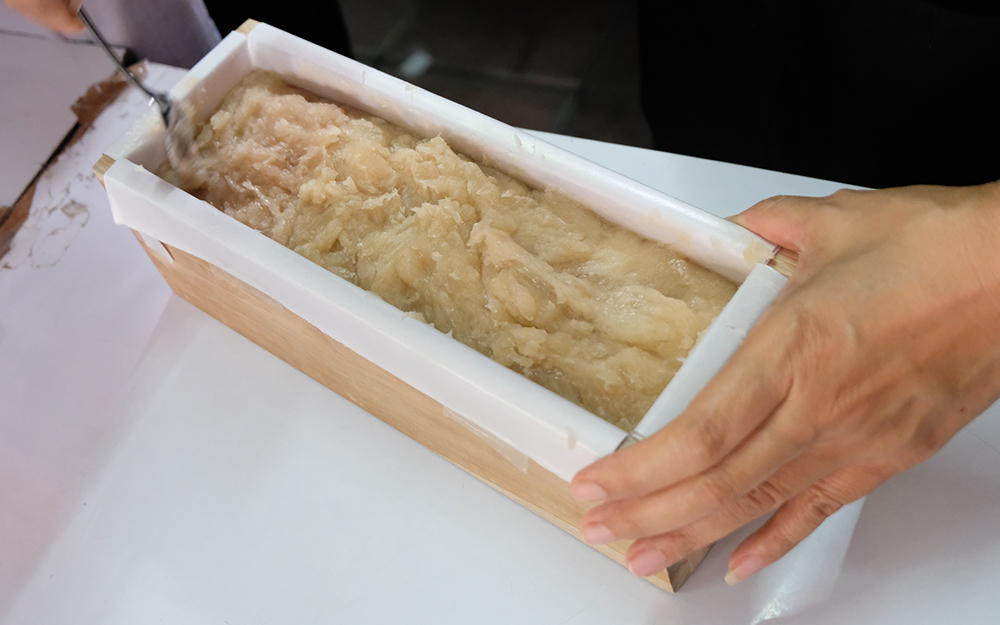 A person smoothing soap into a mold. A person smoothing soap into a mold.