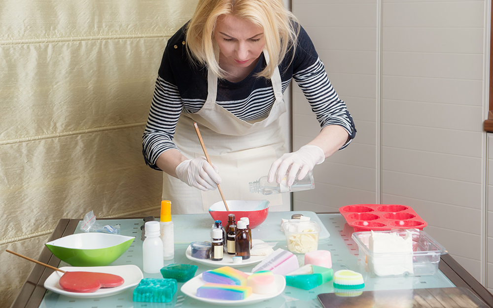 A woman in a apron measuring ingredients for soap making. A woman in a apron measuring ingredients for soap making.
