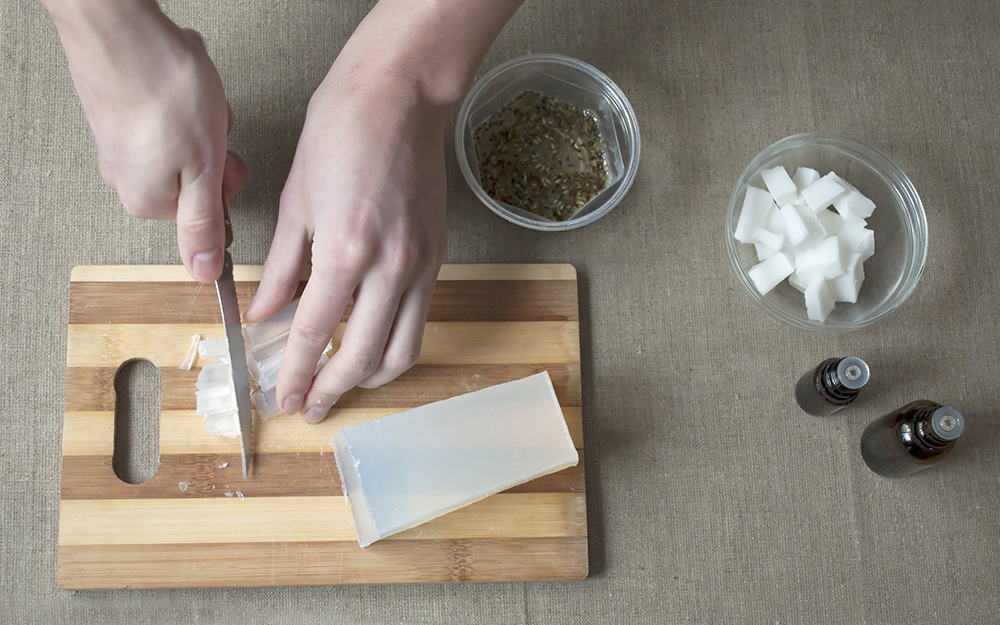 A person cutting clear soap on a cutting board. A person cutting clear soap on a cutting board.