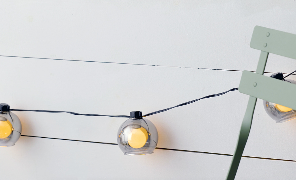String lights hung near a green patio chair. String lights hung near a green patio chair.