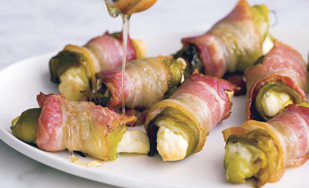 Appetizers consisting of peppers, cream cheese and bacon are drizzled with honey. Appetizers consisting of peppers, cream cheese and bacon are drizzled with honey.