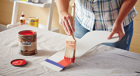 A person paints a wooden stocking.