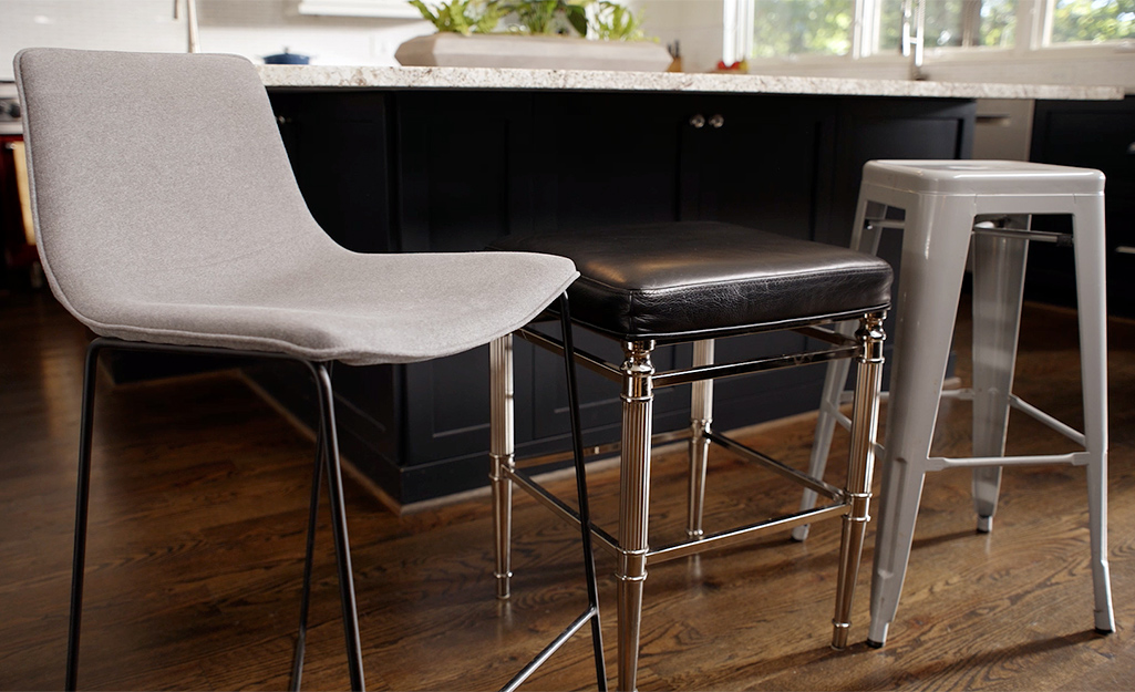 Three types of bar stools placed next to a kitchen counter.