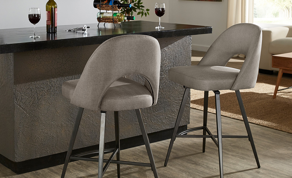 Two upholstered bar stools with backs placed at a bar.