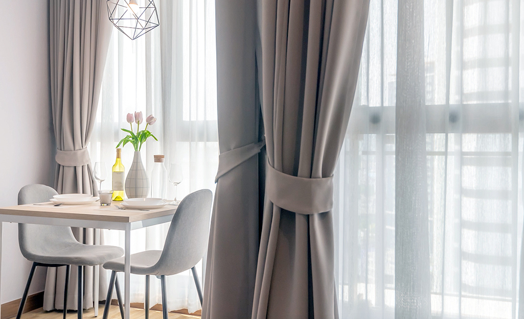 Windows covered with both sheers and drapes in a dining area.