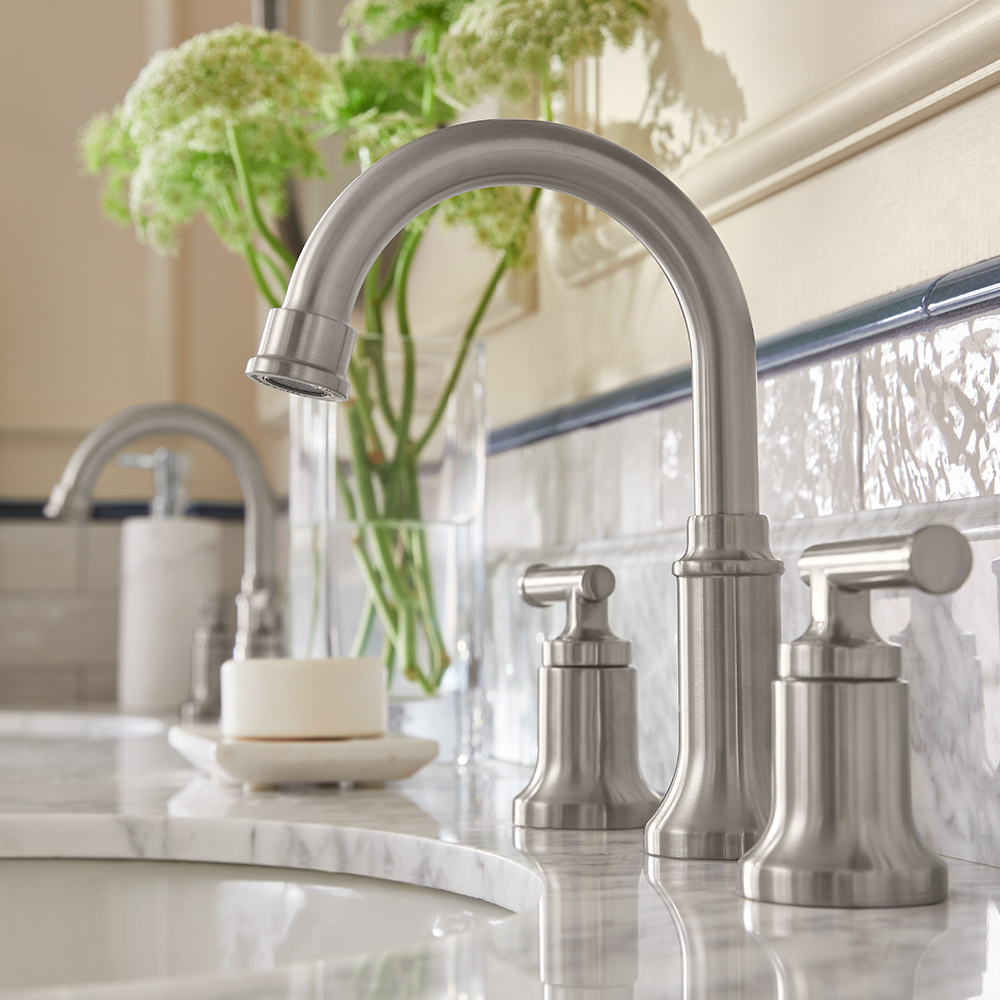 A silver widespread faucet with matching hands is mounted to bathroom countertop.