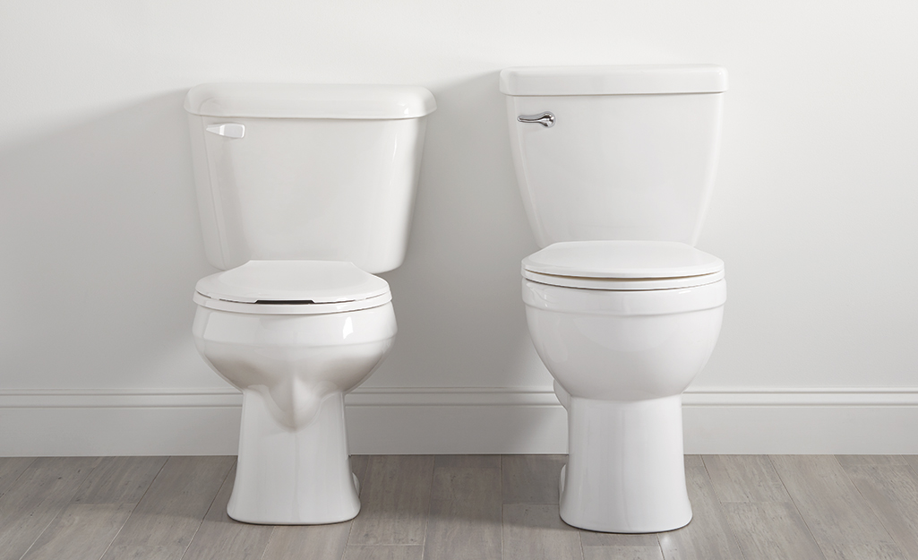 Two white toilets against a wall