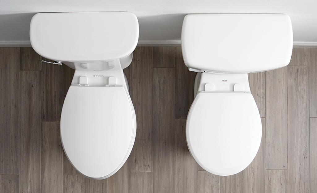 One toilet with an oval shape bowl and one toilet with a round bowl