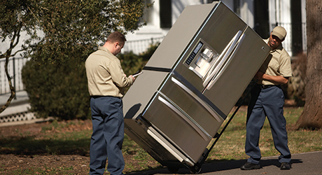 Two men delivering a refrigerator. Two men delivering a refrigerator.