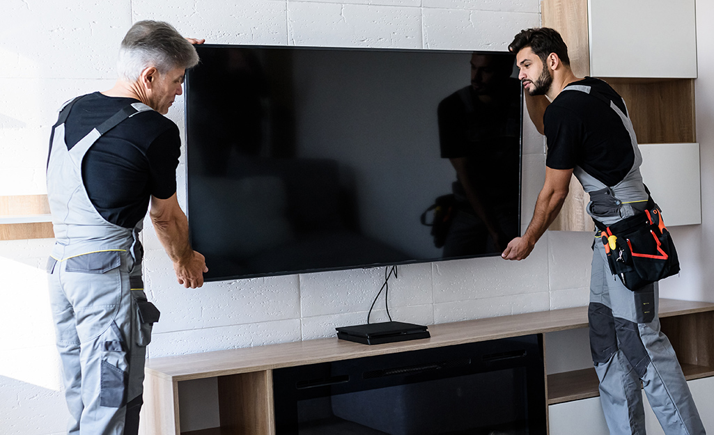 Two people mounting a TV to a wall.