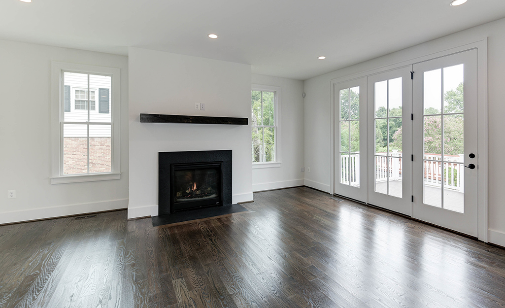 An empty living room with dark wood floor. 