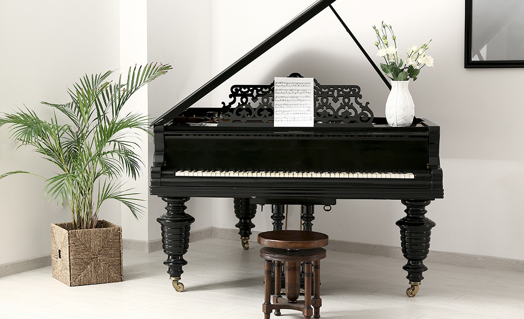 Sheet music rests on the ornate music stand of a grand piano in a white room.