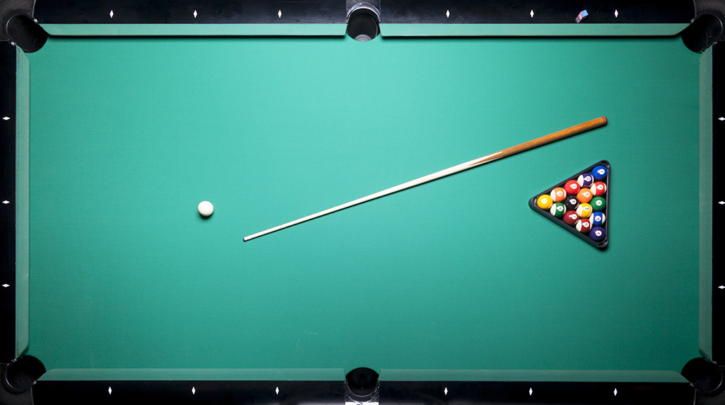 Cue stick and a rack of pool balls lying on a pool table top.