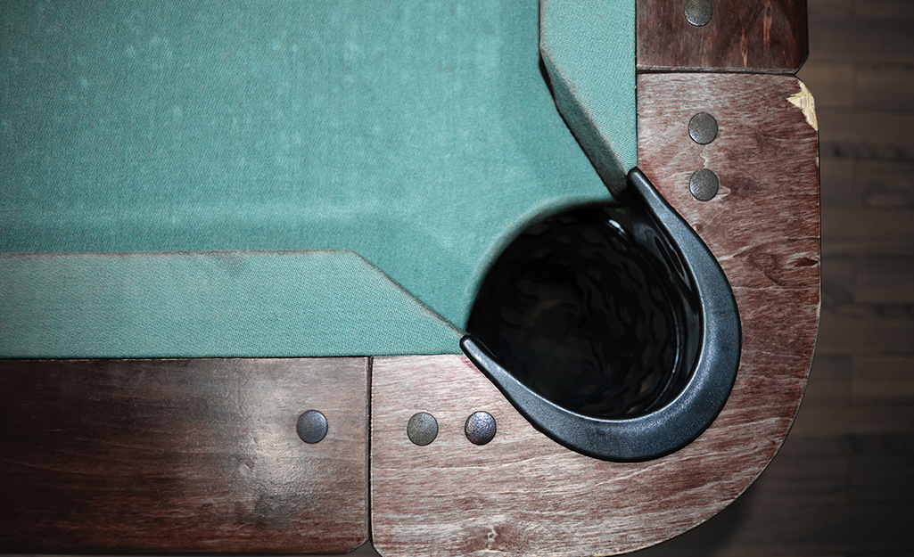 A corner of a pool table showing the screws in the wood.