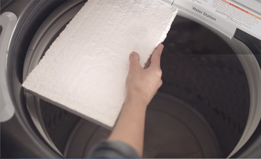 Someone placing foam core in a washer tub.