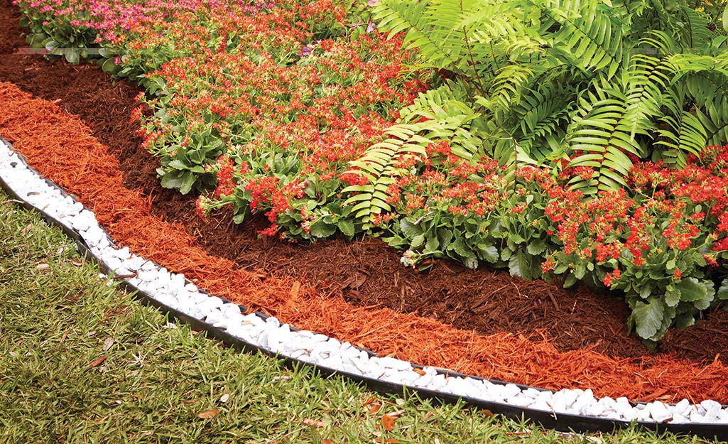 Red dyed mulch in a garden bed with white stone edging.