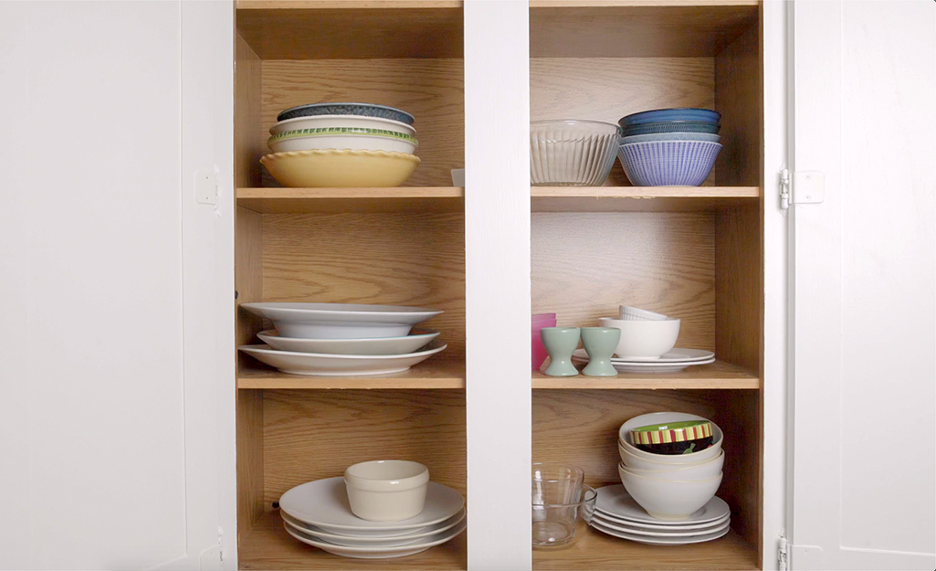 A kitchen cabinet with dishes, cups and saucers.