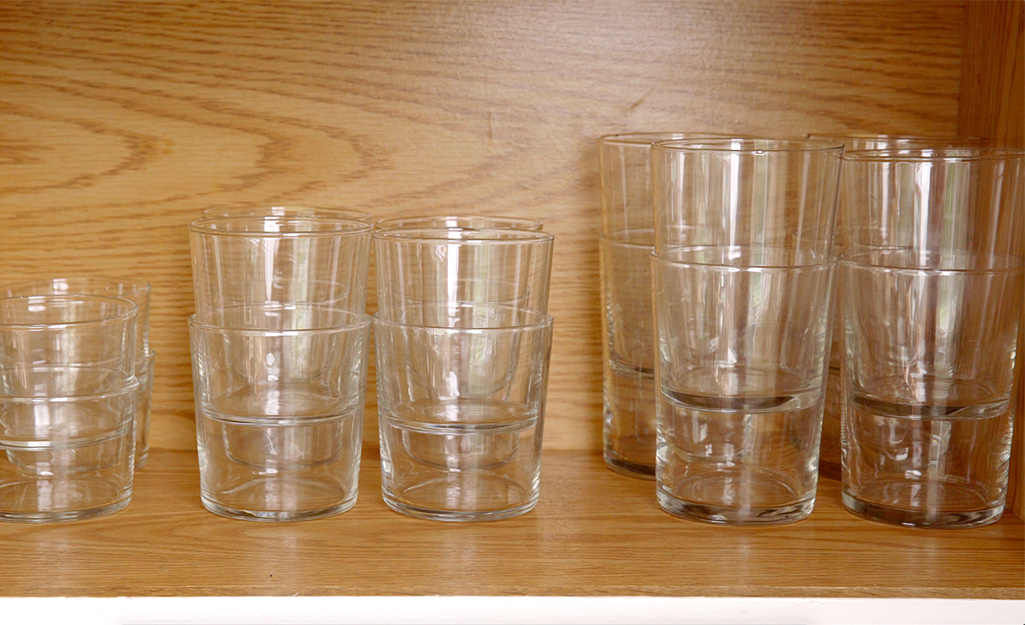Glassware in a cabinet is stacked by size. 