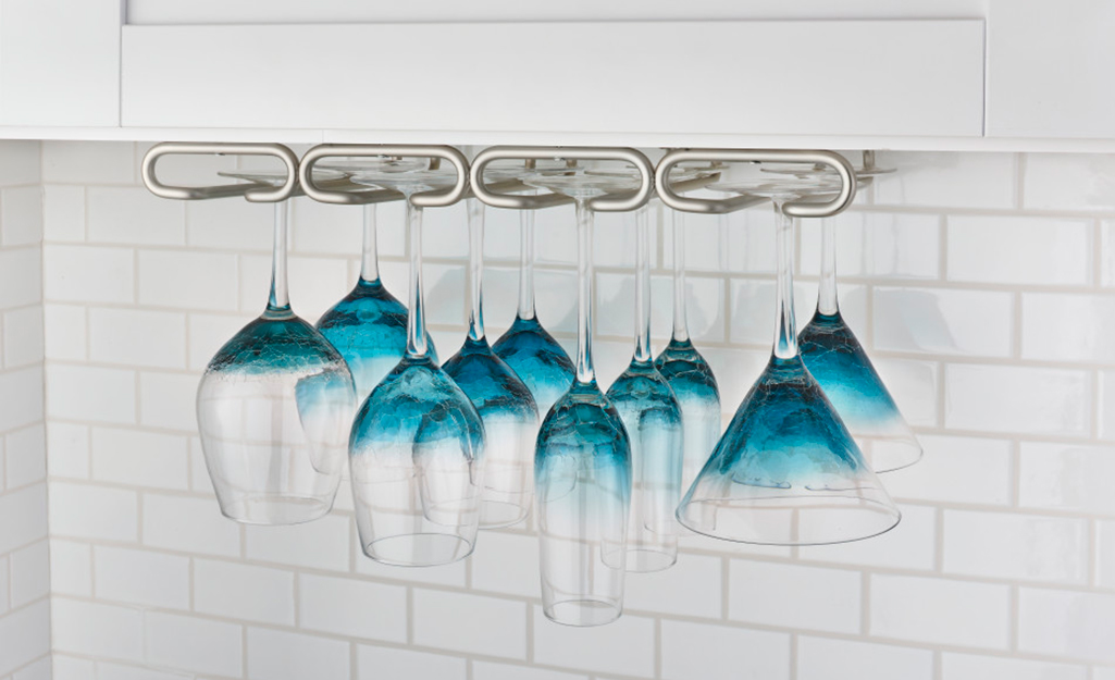 Wine glasses hang from racks under a kitchen counter.