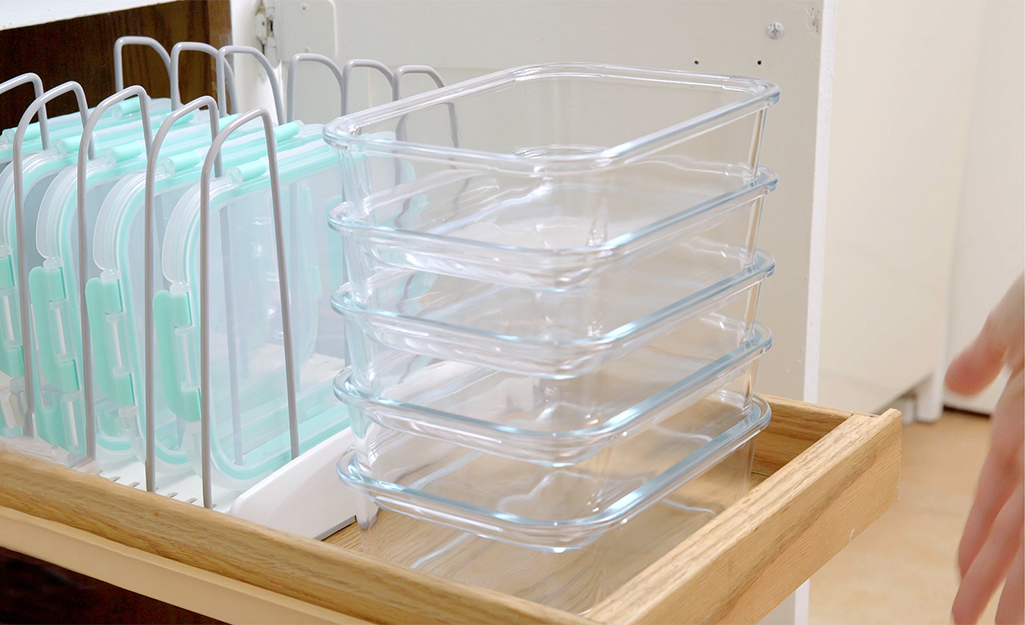 A pull-out cabinet with organized food storage containers.