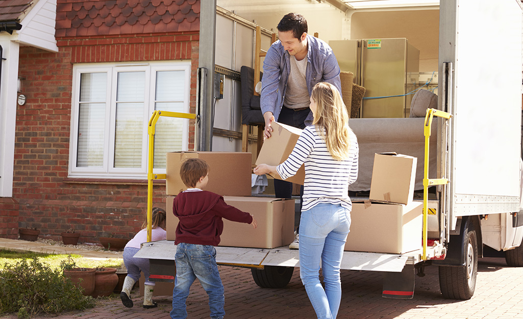 Couple loading small boxes into a moving truck.