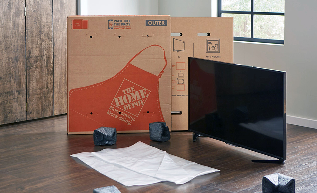 A The Home Depot moving box next to a flat screen TV.