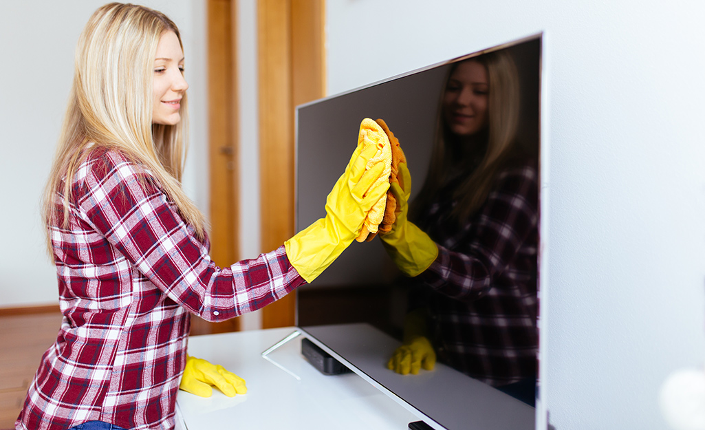 A person cleaning the screen on a TV.