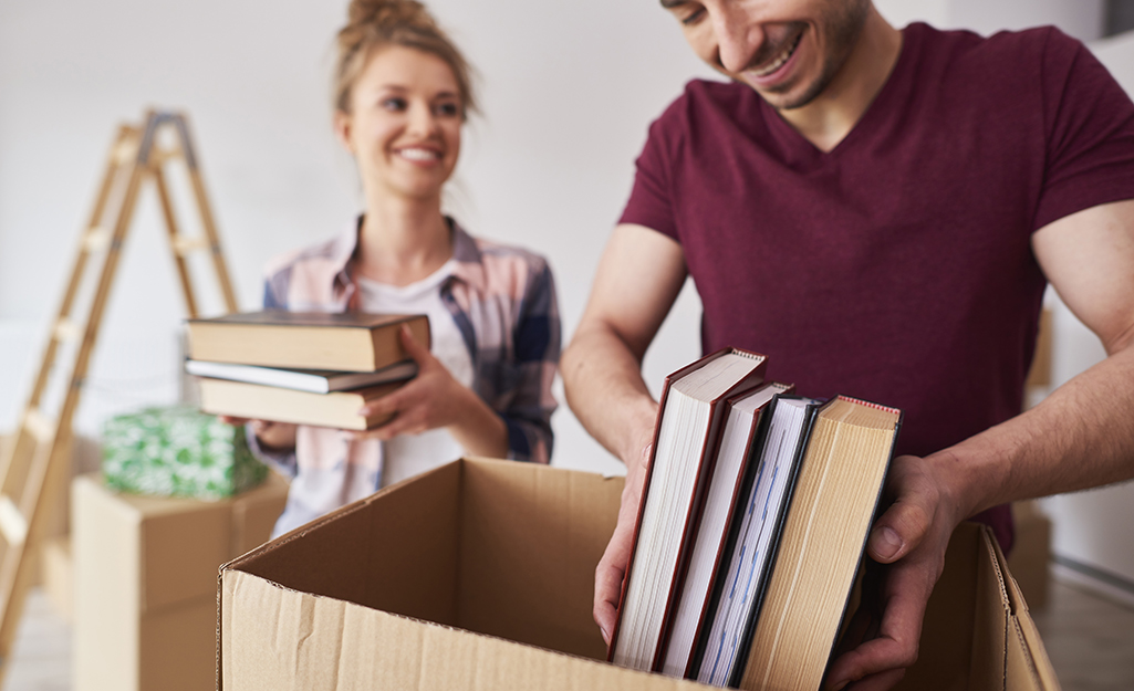 A couple packs a variety of books into moving boxes.