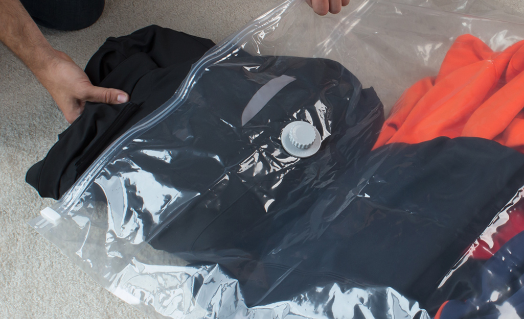 Someone placing bulky clothing into a vacuum bag.