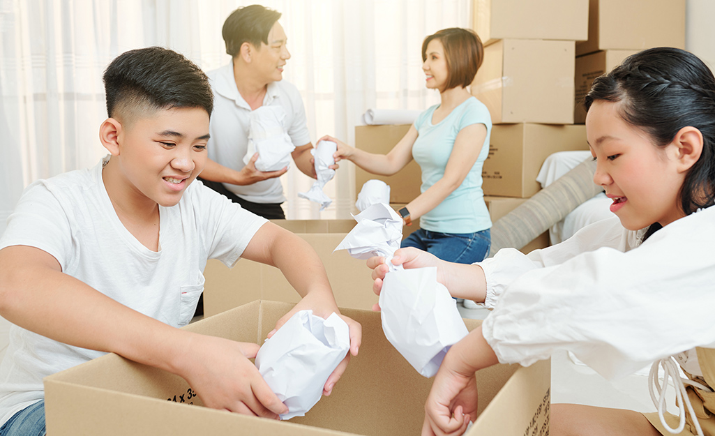 Four people placing wrapped glasses into boxes.