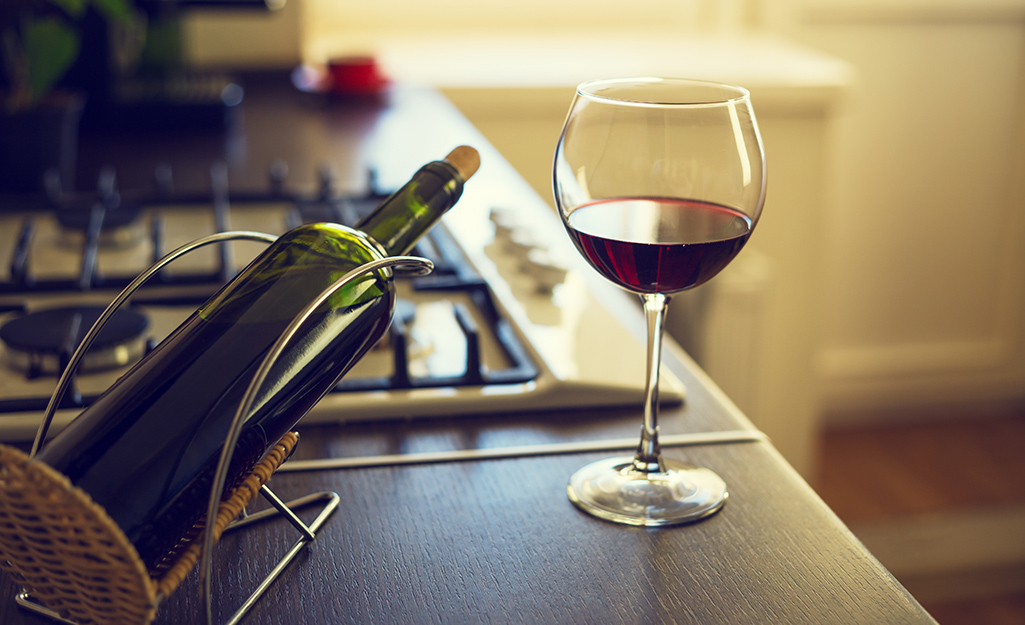 A wine glass with red wine in it on a kitchen counter.