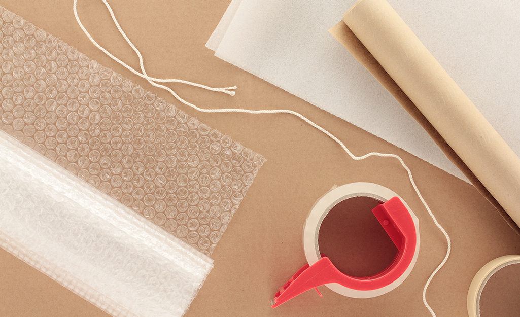 Bubblewrap, string and packing tape lying on top of packing paper.