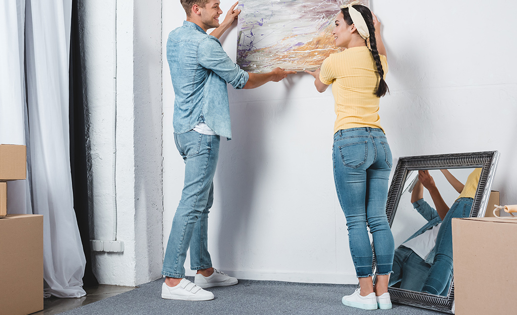 Couple removing stretched canvas wall art from wall.