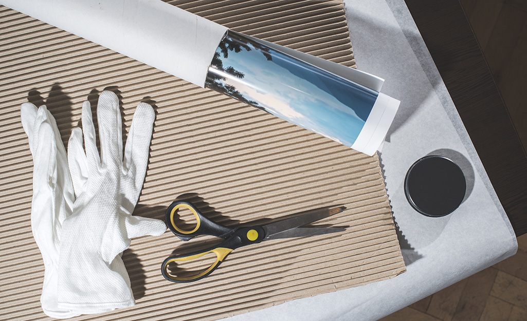 Rolled art work, tissue paper and scissors placed on top of packing paper.