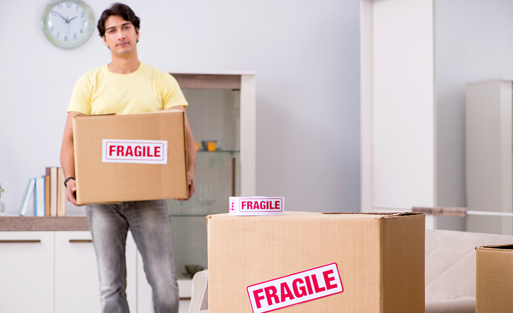 Man placing carrying a moving box marked fragile.