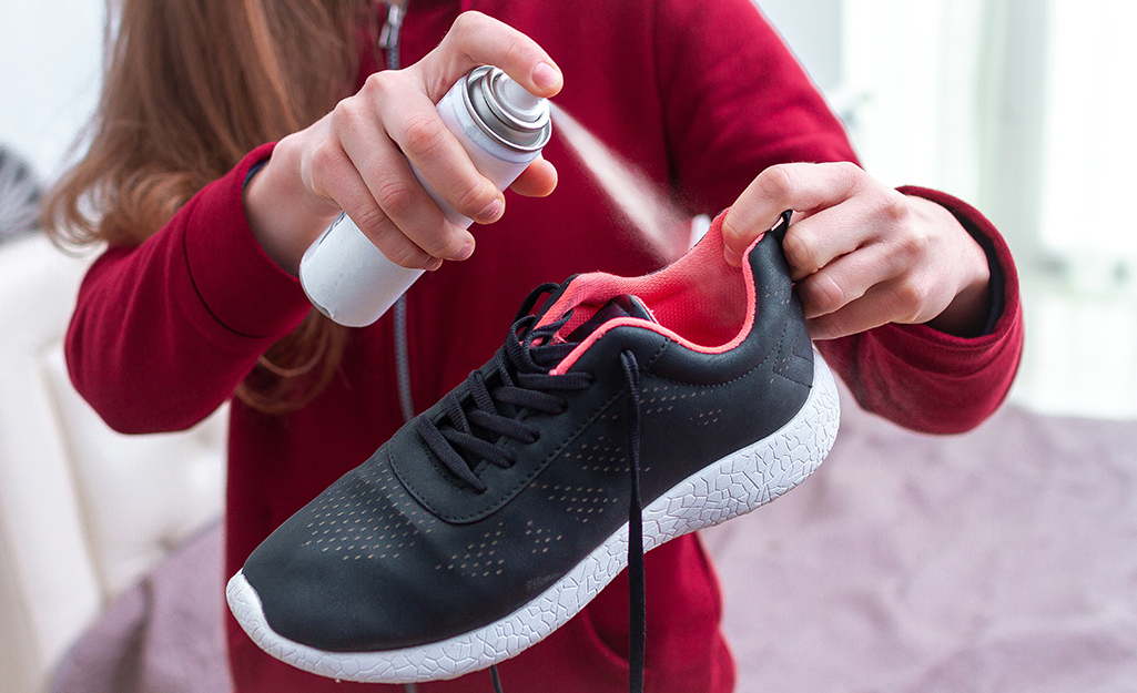 Someone spraying a sneaker with deodorizing spray.