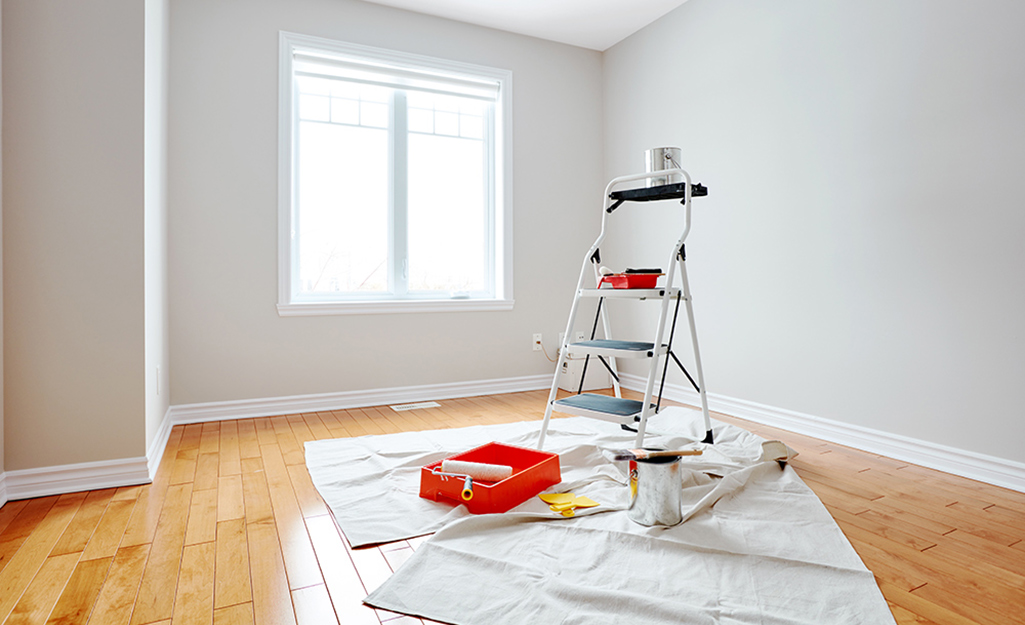 A step ladder and other paint supplies stand in a painted room.