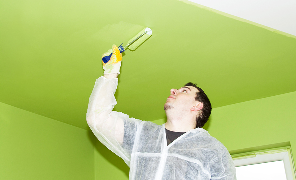 A person paints a ceiling with a roller.