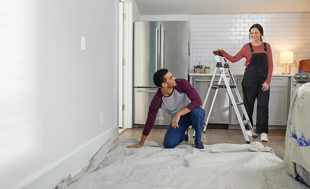 A man and woman prep a room for painting.