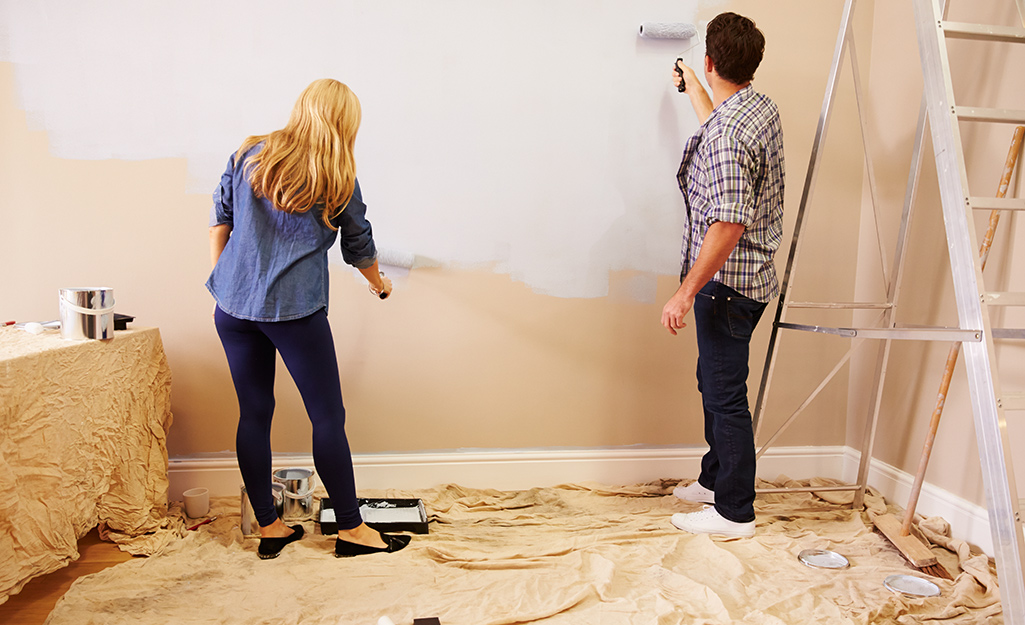 A couple painting a wall.