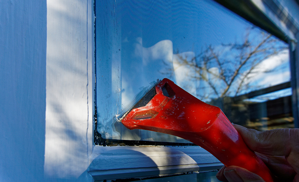 Someone scraping paint off of a exterior window pane.