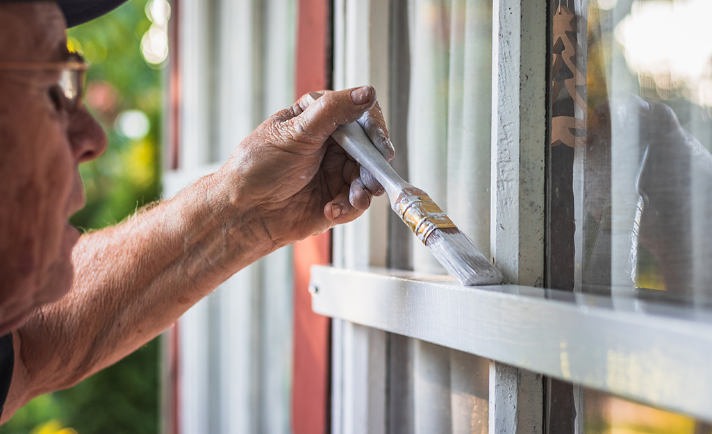 Someone painting the sash of an exterior window.