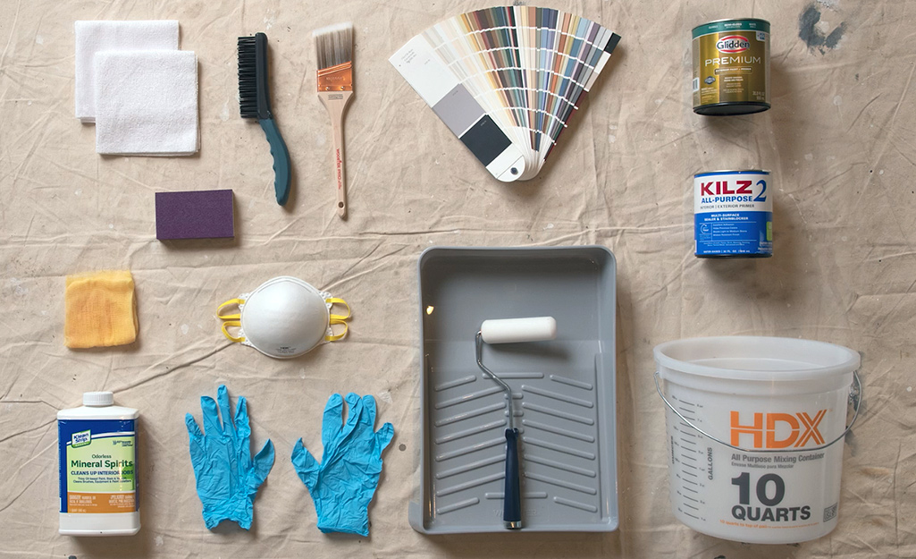A roller, brushes and other paint supplies gathered on a table.