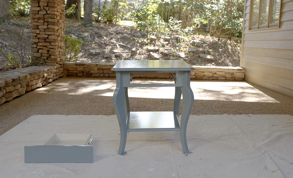 A newly painted small wood table drying in a breezeway.